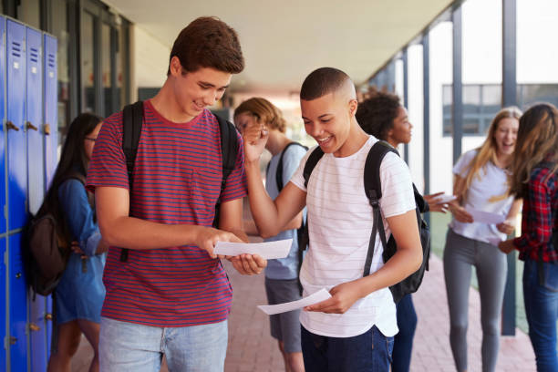 Happy teenage boys sharing exam results in school corridor Happy teenage boys sharing exam results in school corridor students exam results stock pictures, royalty-free photos & images