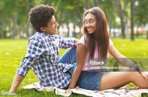 Happy teenage couple resting in park, looking at each other