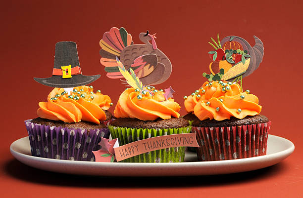 Happy Thanksgiving cupcakes with turkey, feast, and pilgrim hat decorations. Happy Thanksgiving cupcakes with turkey, feast, and pilgrim hat topper decorations against a harvest red brown background. turkey cupcakes stock pictures, royalty-free photos & images
