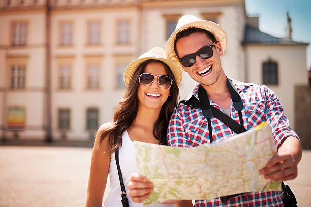 Happy tourists couple holding map Happy tourists couple holding map  tourism stock pictures, royalty-free photos & images