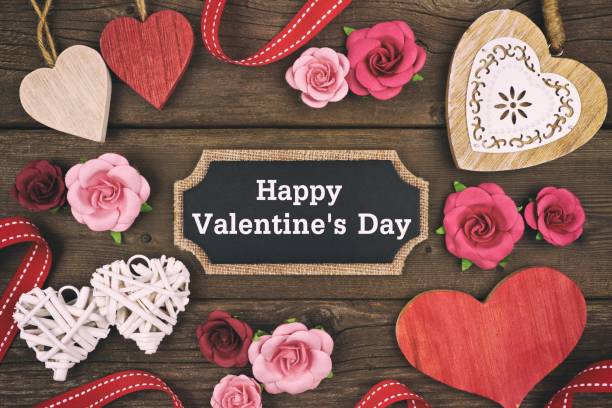 Happy Valentines Day chalkboard tag with frame of hearts and flowers Happy Valentines Day message on a chalkboard tag with frame of hearts and flowers on a wooden background. Vintage styling. happy valentines day stock pictures, royalty-free photos & images
