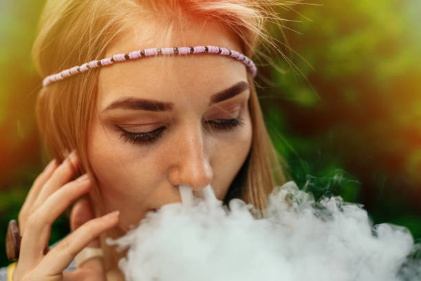Happy vaping young white blonde girl technologies, beauty and lifestyle concept -Happy vaping young white blonde girl. smoking fruit flavored e-liquid or e-juice with vaporizer device or e-cig.Modern gadget for smokers vape kits stock pictures, royalty-free photos & images