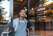 istock Happy waiter opening on the doors at a cafe 1003743970