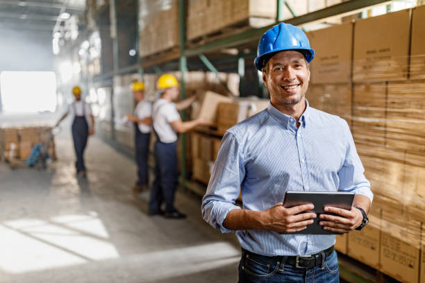 Happy warehouse manager using touchpad in a storage room. stock photo