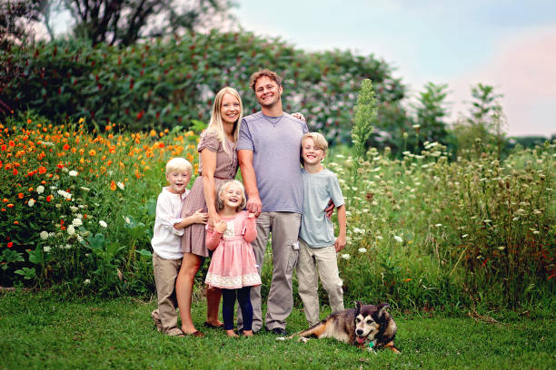 幸せな健全な白人家族と犬の笑顔と花でポーズ - キリスト教 写真 ストックフォトと画像