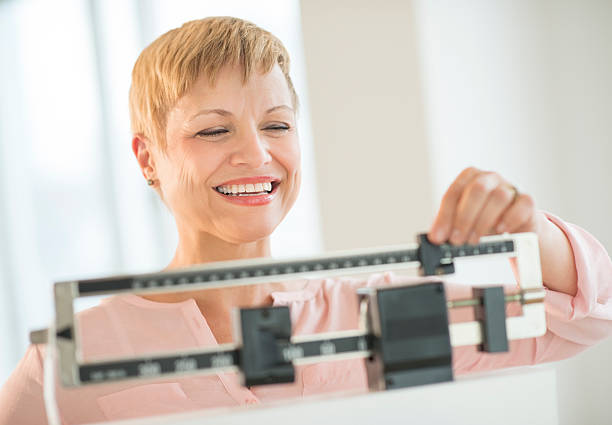 Happy Woman Adjusting Balance Weight Scale stock photo