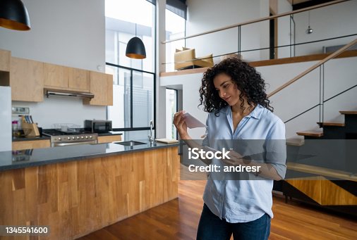 istock Happy woman at home checking letters in the mail 1345541600
