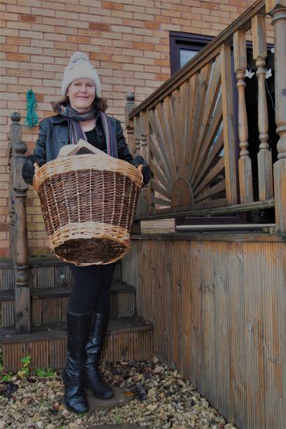 happy woman carrying a basket of wood for the fire. - idosos aquecedor imagens e fotografias de stock