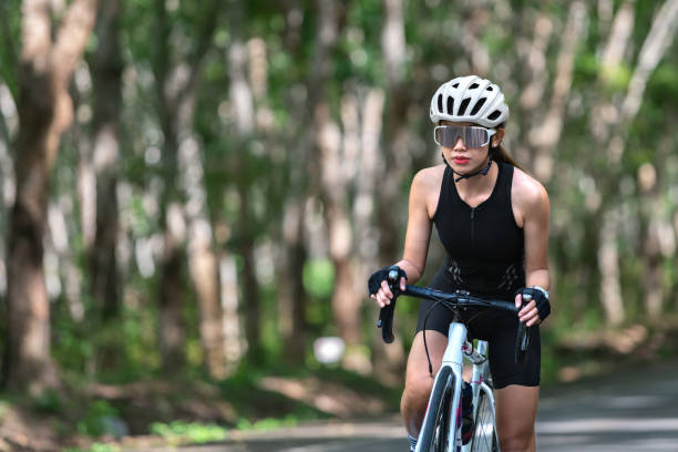 happy woman cycling athlete prepare for ride bicycle on street, road, with high speed for exercise hobby and competition in professional tour stock photo