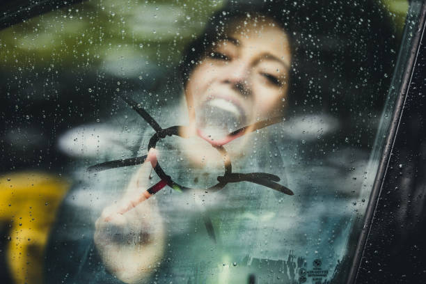 gelukkige vrouw het tekenen van zon op autoruit tijdens regenachtige dag. - rain woman sun stockfoto's en -beelden