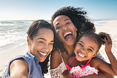 istock Happy woman friends with child taking selfie at seaside 1369510051