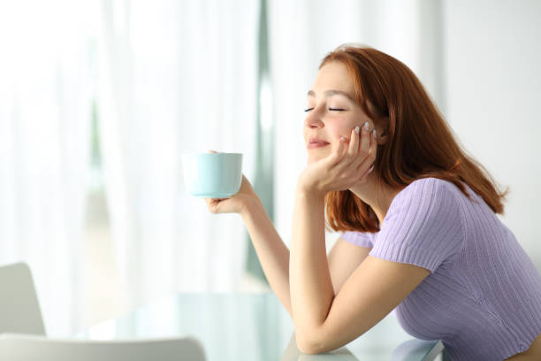 Happy woman holding coffee cup resting in apartment stock photo