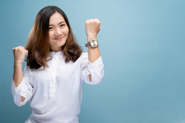 happy woman holding hand met polshorloge geïsoleerd op een blauwe achtergrond - woman horloge stockfoto's en -beelden