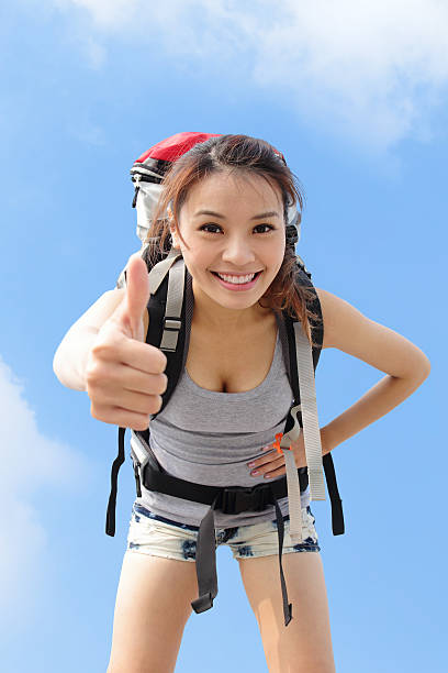 happy woman mountain hiker show thumb up with sky background. asian