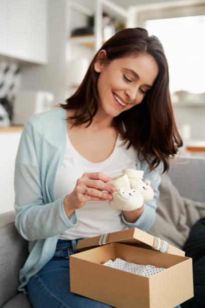 Happy woman puts knit baby booties into gift box stock photo