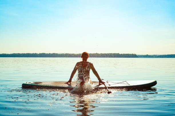 Happy woman relaxes on SUP board and enjoy life stock photo