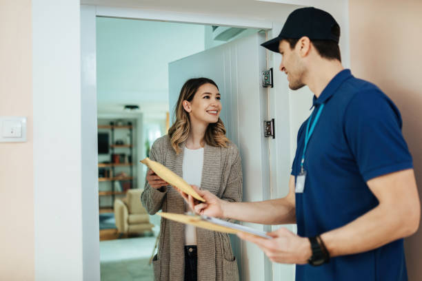 Happy woman taking package from delivery man at her doorway. Young happy woman talking to a courier while receiving home delivery. home delivery stock pictures, royalty-free photos & images