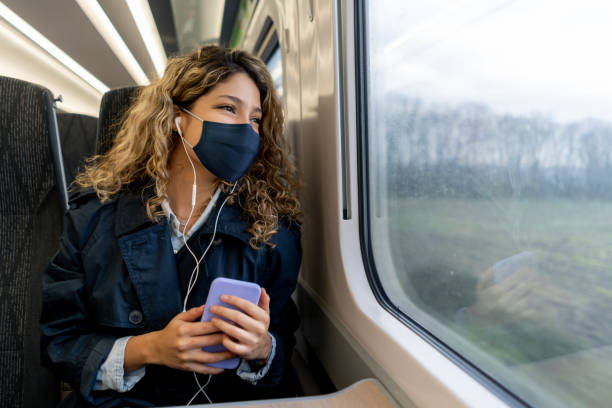 femme heureuse voyageant par train utilisant un masque facial - train photos et images de collection