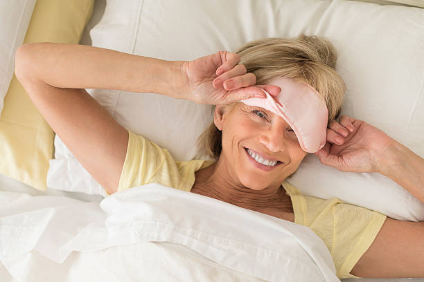Happy Woman Wearing Sleep Mask On Bed stock photo