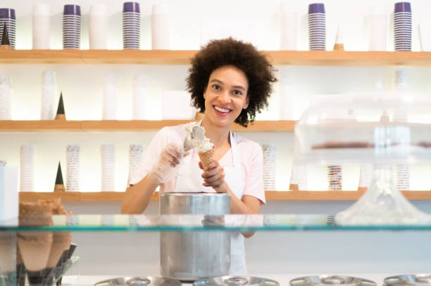 Happy woman working at an ice cream parlor stock photo