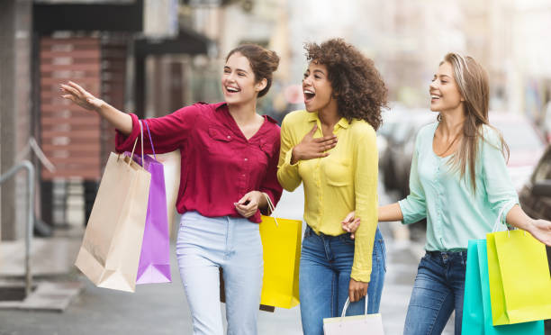 gelukkig vrouwen met boodschappentassen wandelen langs stad straat - etalages kijken stockfoto's en -beelden
