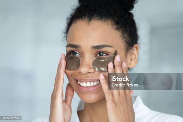 Happy young african american woman applying patches.