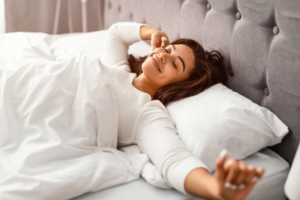 Happy young African American woman stretching arms after waking up stock photo