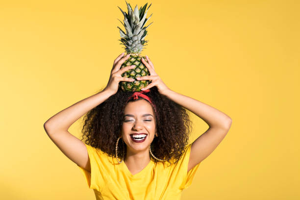パイナップルの頭の上に保持している幸せな若いアフロ女 - パイナップル 女性 ストックフォトと画像
