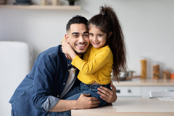 Happy Young Arab Dad And Little Daughter Posing Together In Kitchen Interior Portrait Of Happy Young Arab Dad And Little Daughter Posing Together In Kitchen Interior, Cute Small Girl Embracing Her Middle Eastern Father And Smiling At Camera, Daddy And Kid Having Fun At Home hot arabic girl stock pictures, royalty-free photos & images