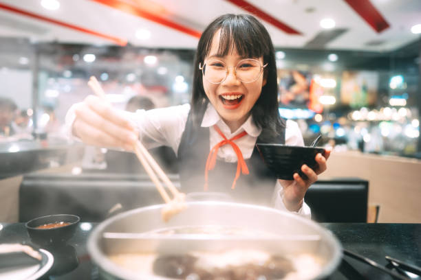 Happy young asian woman japanese thai student eating shabu japan sukiyaki restaurant. stock photo