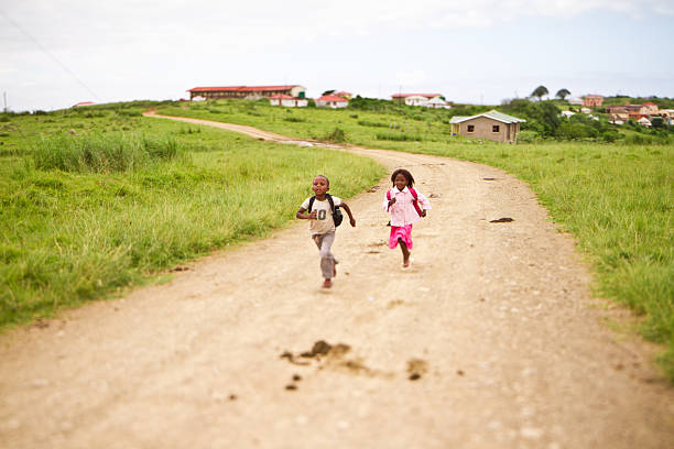 Happy young brother and sister running to school together stock photo