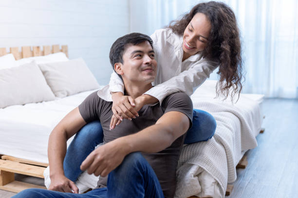 Happy young couple hugging and laughing in bedroom. stock photo