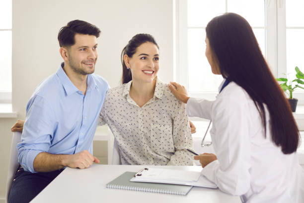 Happy young couple planning pregnancy and visiting their family practitioner together stock photo