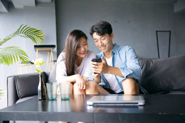 Happy young couple share information on mobile phone stock photo