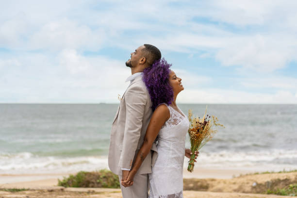 Happy young couple with their backs to each other Newlyweds, Back to back, Happy, Hand in hand, Beach fiancé stock pictures, royalty-free photos & images