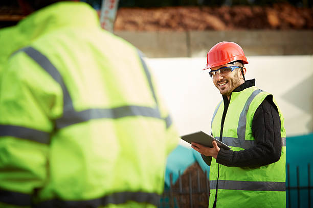 Happy young engineer with digital tablet at site stock photo