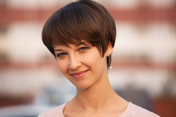 Happy young fashion woman with pixie hair on city street stock photo