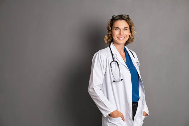 happy young female doctor on grey wall - doctor wall imagens e fotografias de stock