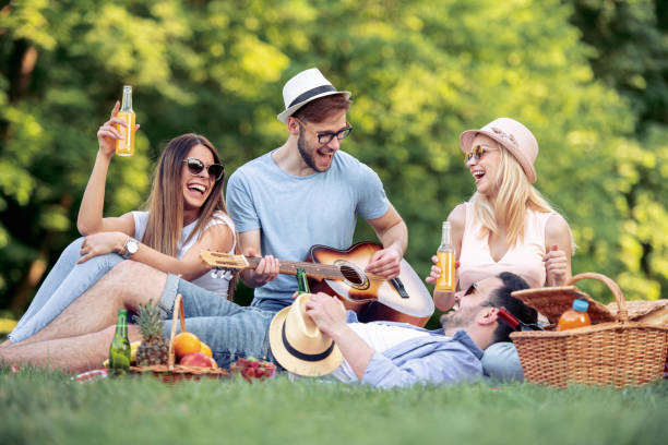 Happy young friends having picnic in the park stock photo