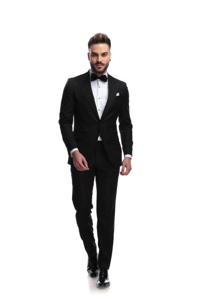 happy young male fashion model in tuxedo is walking happy young male fashion model in tuxedo is walking on white background tuxedo stock pictures, royalty-free photos & images