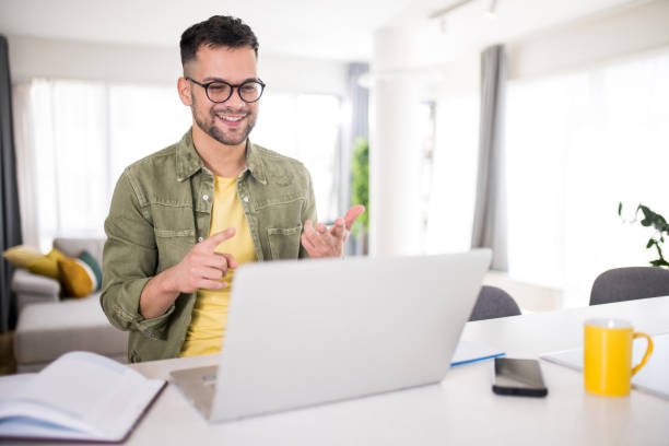 Happy young man having an online consultation session at home. stock photo