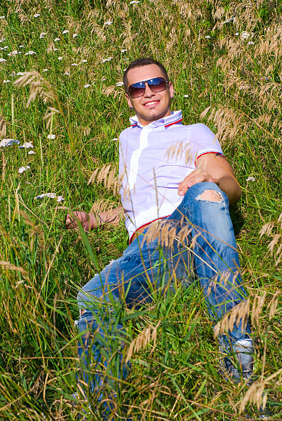 Happy young man in grass stock photo