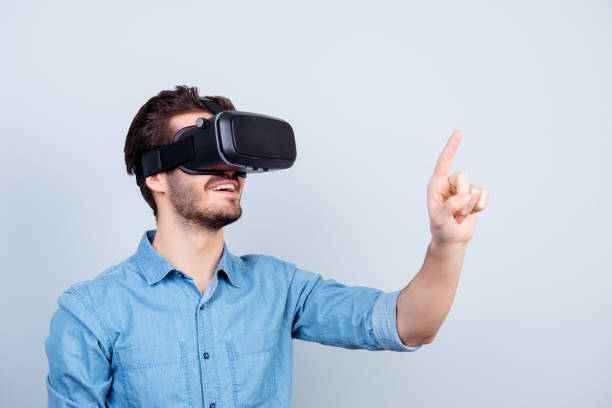 glücklicher junger mann nutzt vh kopfhörer brille der virtuellen realität auf sopmething mit finger zeigen - vr brille stock-fotos und bilder