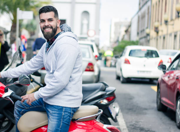 happy young man parking red scooter - cargo canarias imagens e fotografias de stock