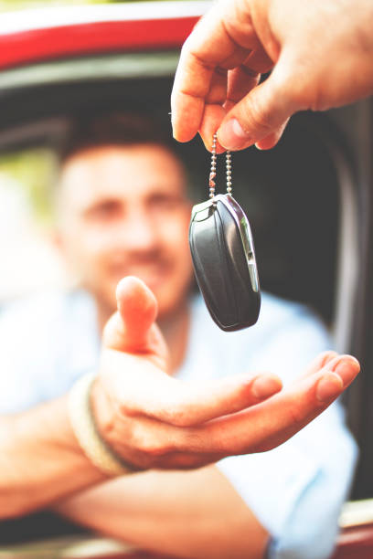 Happy young man receiving keys of his new car stock photo