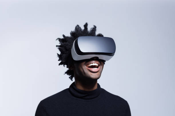 Happy young man using virtual reality glasses Portrait of excited afro american man wearing virtual reality glasses, standing against grey background. vr stock pictures, royalty-free photos & images