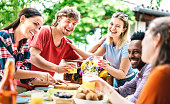 istock Happy young men and women toasting healthy orange fruit juice at farm house picnic - Life style concept with alternative friends having fun together on afternoon relax time - Bright vivid filter 1350827450