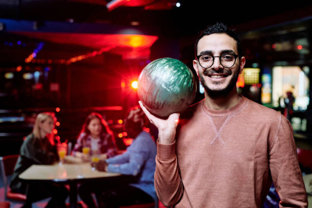 happy young mixed-race man with bowling ball spending time at leisure center - balo~es festa imagens e fotografias de stock