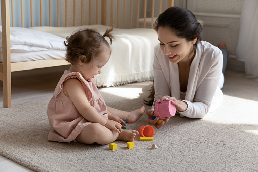 Image of an Asian Chinese mother holding a toy and playing with her baby at home