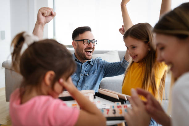 Happy young parents and children having fun, playing board game at home Happy parents and children having fun, playing board game at home board game photos stock pictures, royalty-free photos & images